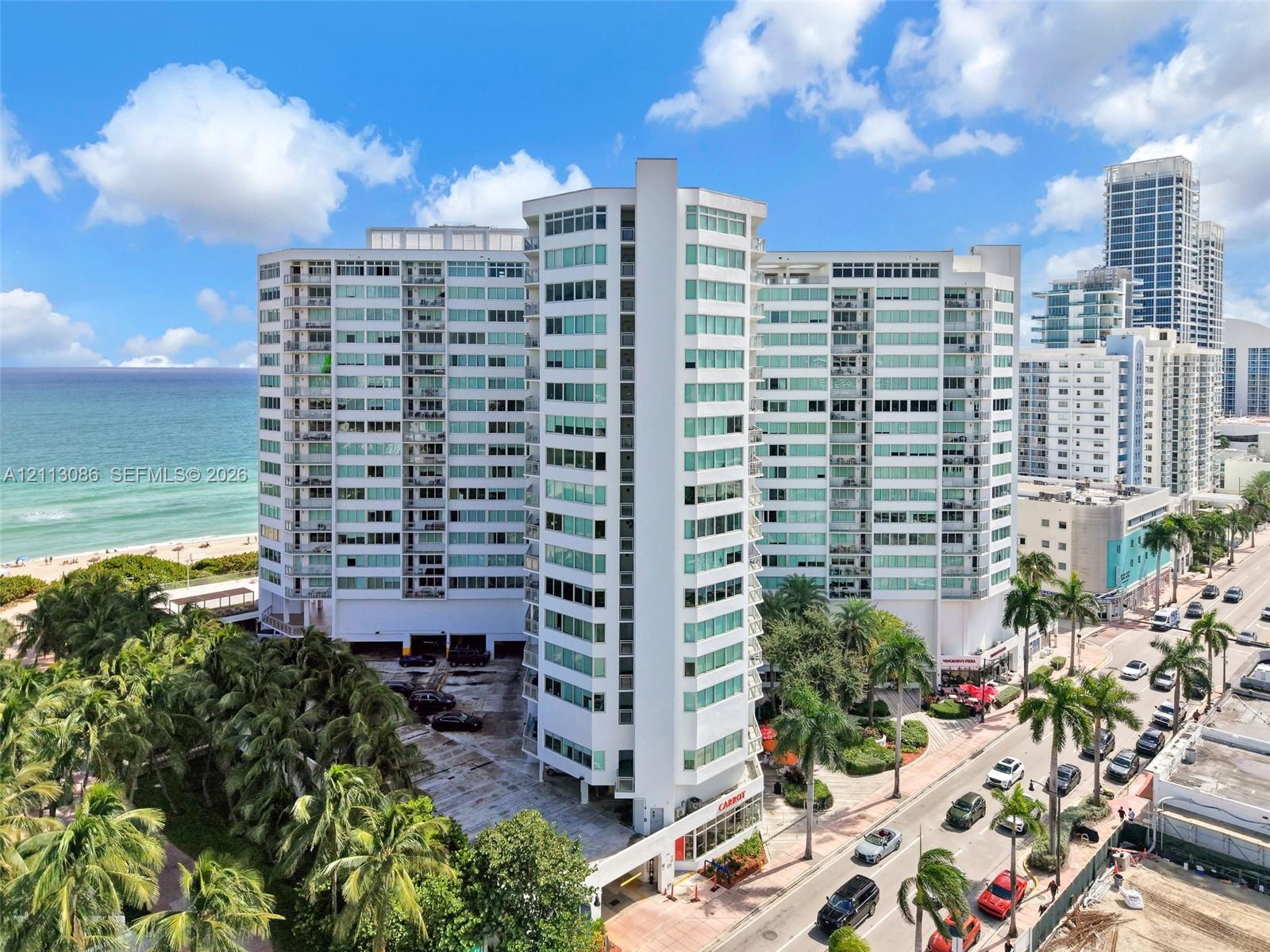 High-rise residential building featuring a glass-paneled facade, private balconies, covered parking, and proximity to the oceanfront