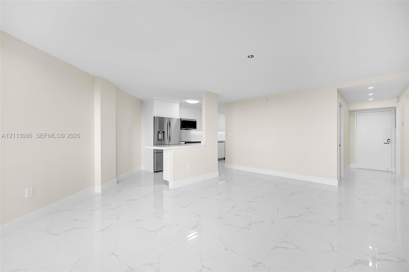 Open-concept interior featuring large-format tile flooring with a veined pattern, a breakfast bar with a solid surface countertop, stainless steel kitchen appliances, and recessed ceiling lighting