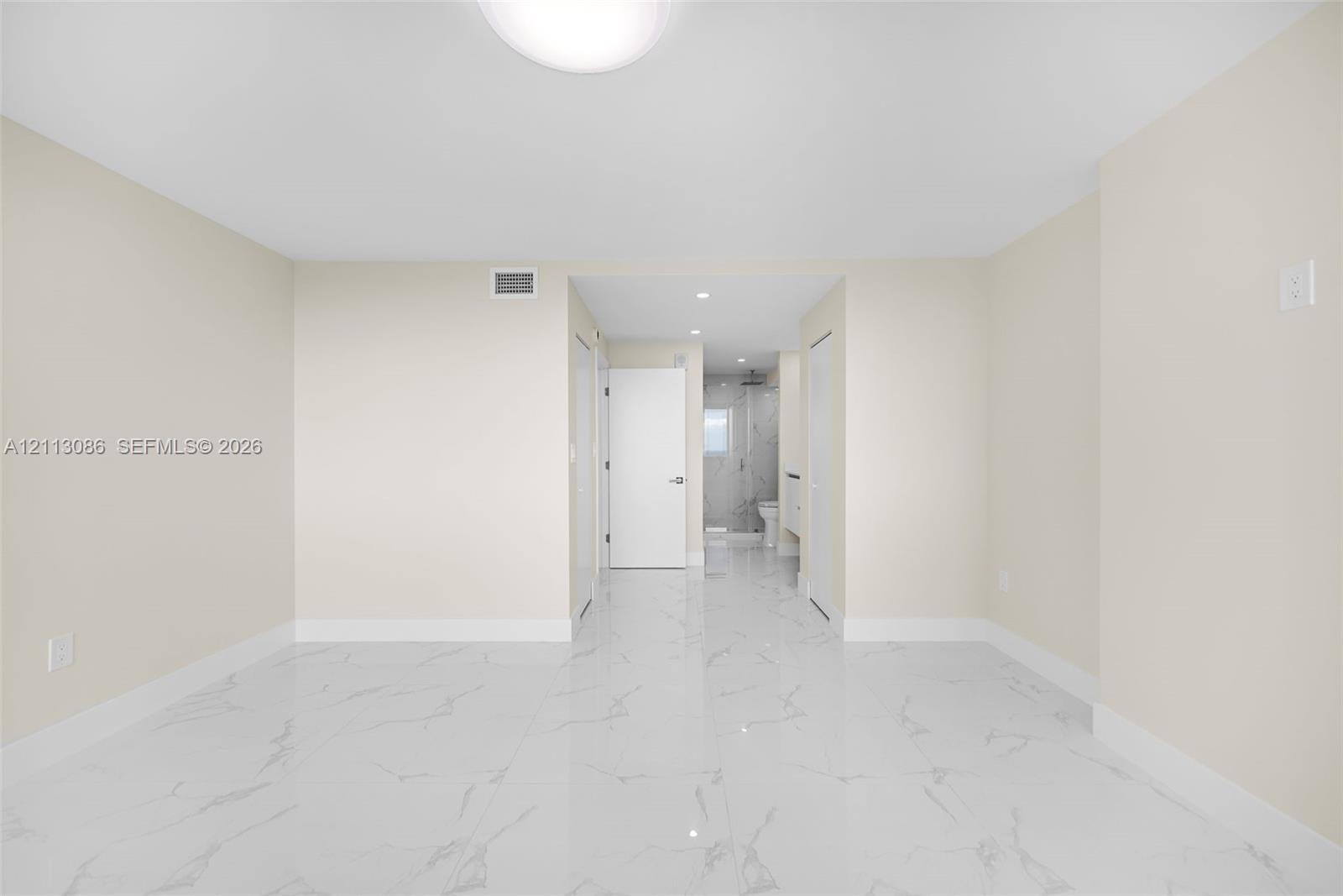 Bright interior space featuring polished white tile flooring with grey veining, crisp neutral walls, and recessed lighting
