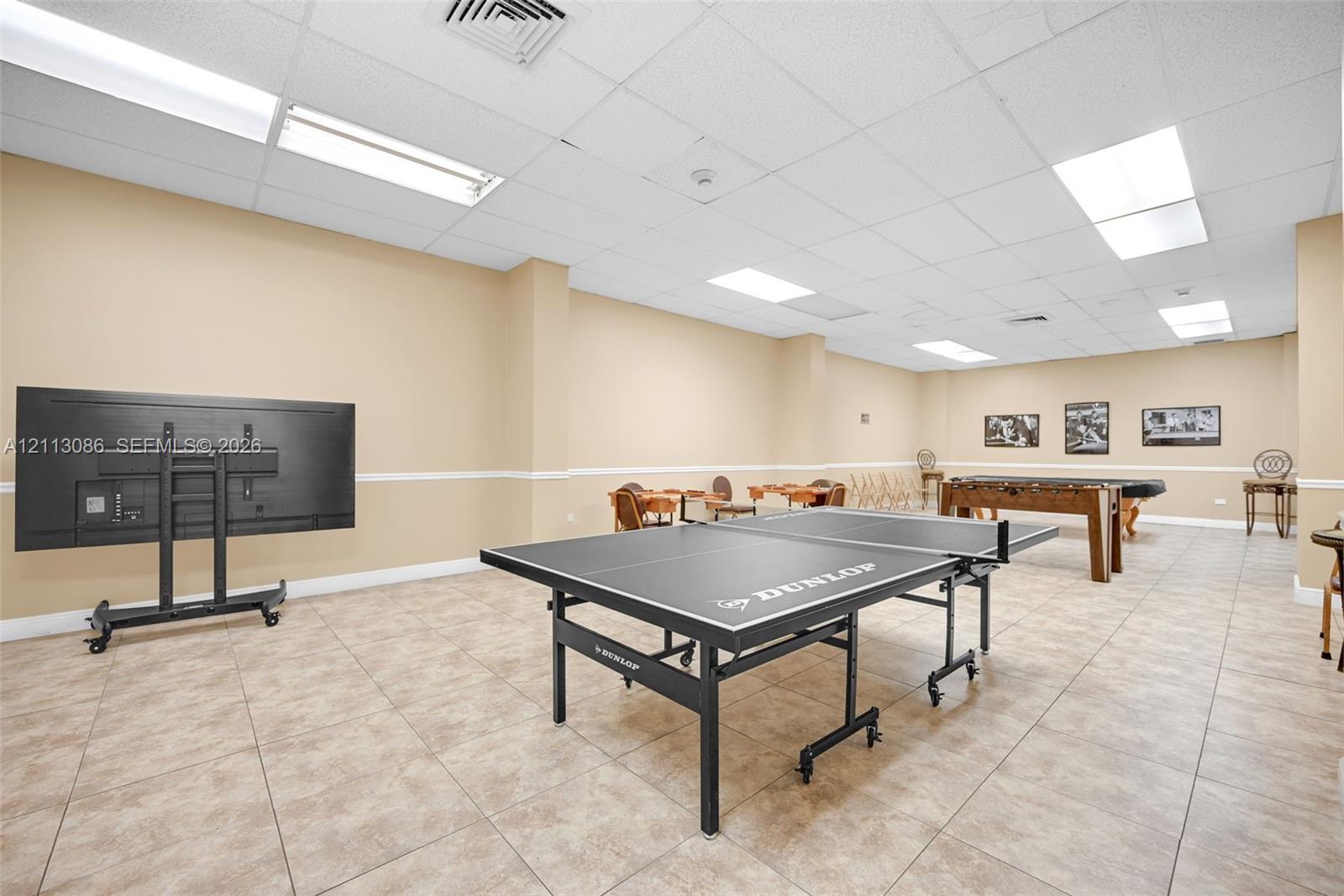 Open-concept interior space featuring neutral wall paint, tile flooring, recessed drop-ceiling grid lighting, and chair rail molding