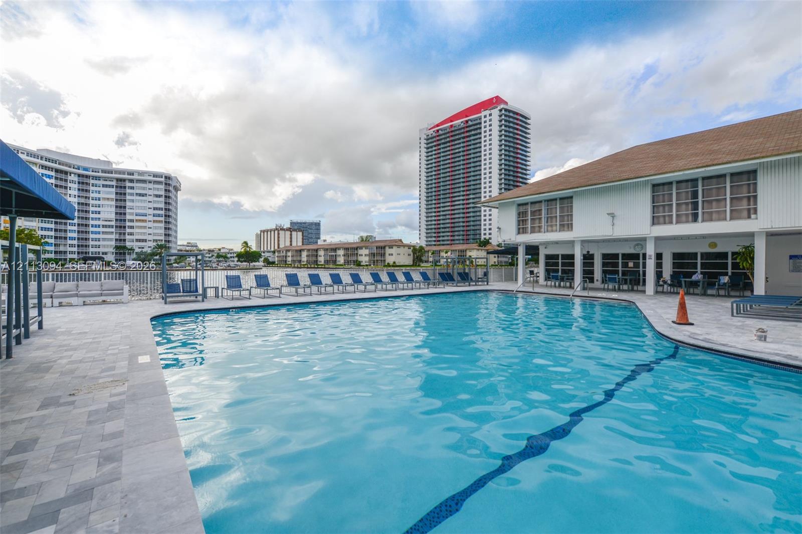 Swimming pool with stone paver decking, multi-story building exterior, and waterfront placement