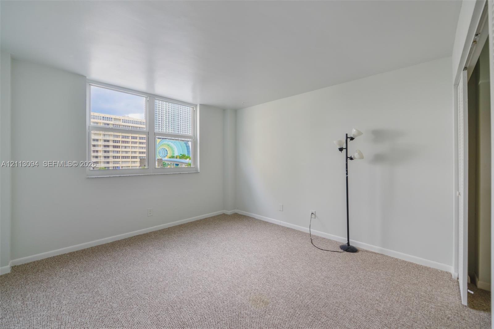 Neutral-toned interior space featuring wall-to-wall carpeting and an expansive multi-pane window