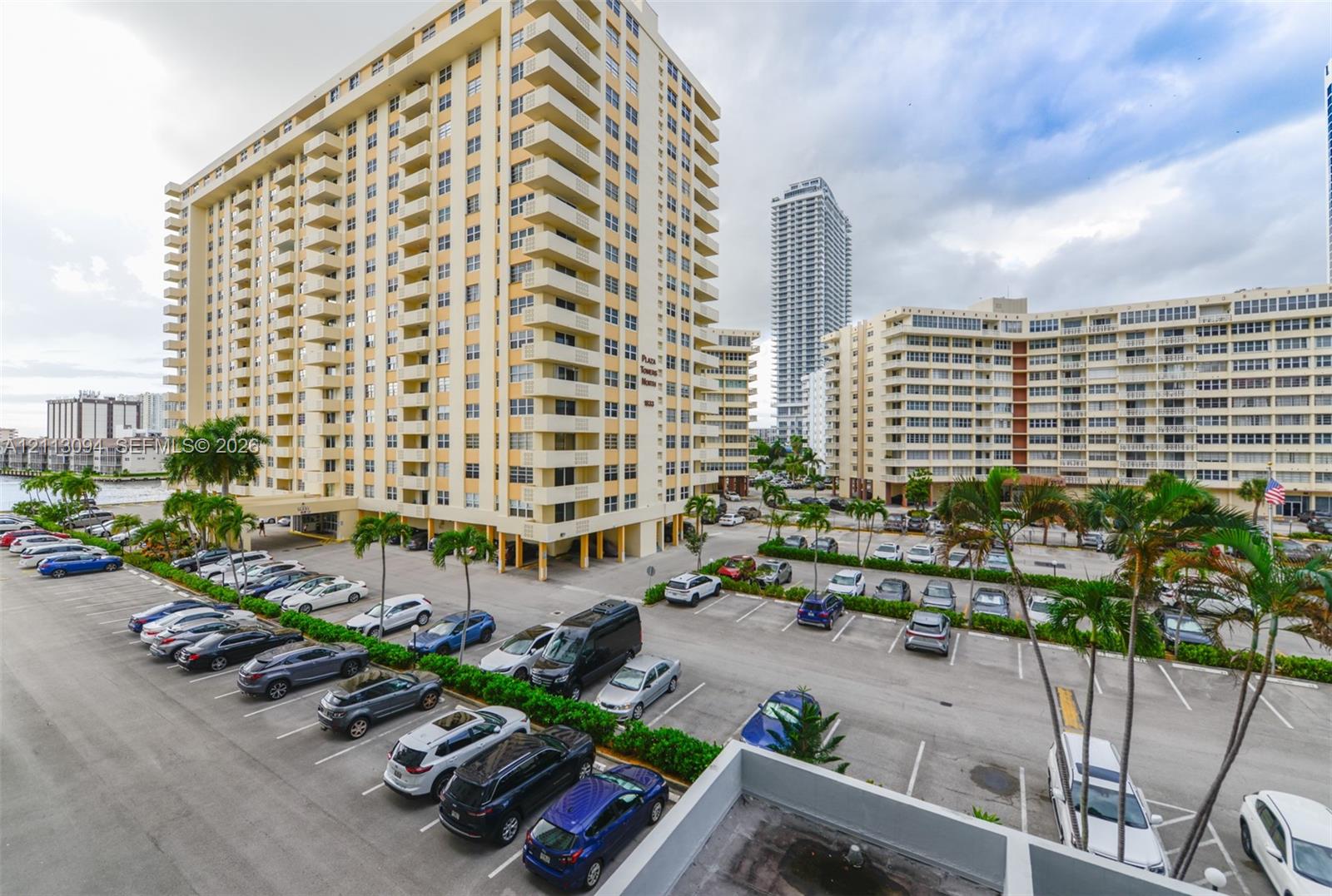 High-rise residential exterior featuring private balconies, surface parking, and manicured landscaping