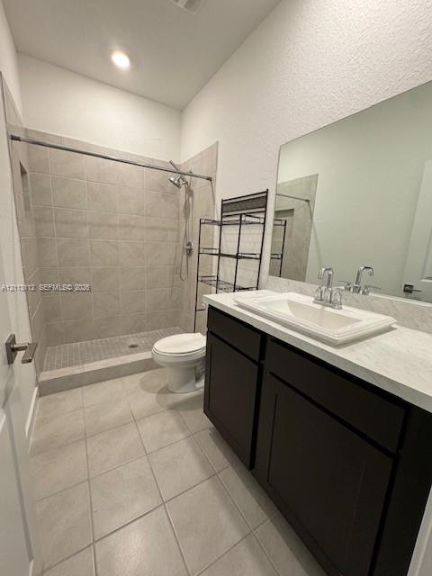 Bathroom featuring a walk-in shower with tile surround, dark-finish cabinetry, light-toned countertop with an integrated basin, and large wall-mounted mirror
