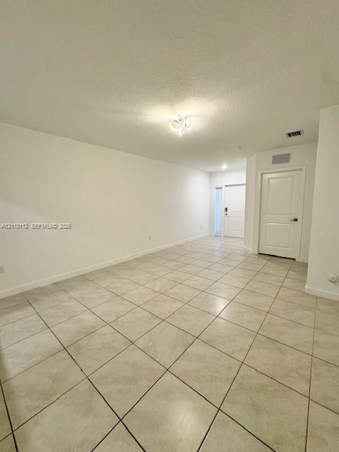 Neutral-toned ceramic tile flooring, multi-panel interior door, and decorative flush-mount ceiling lighting