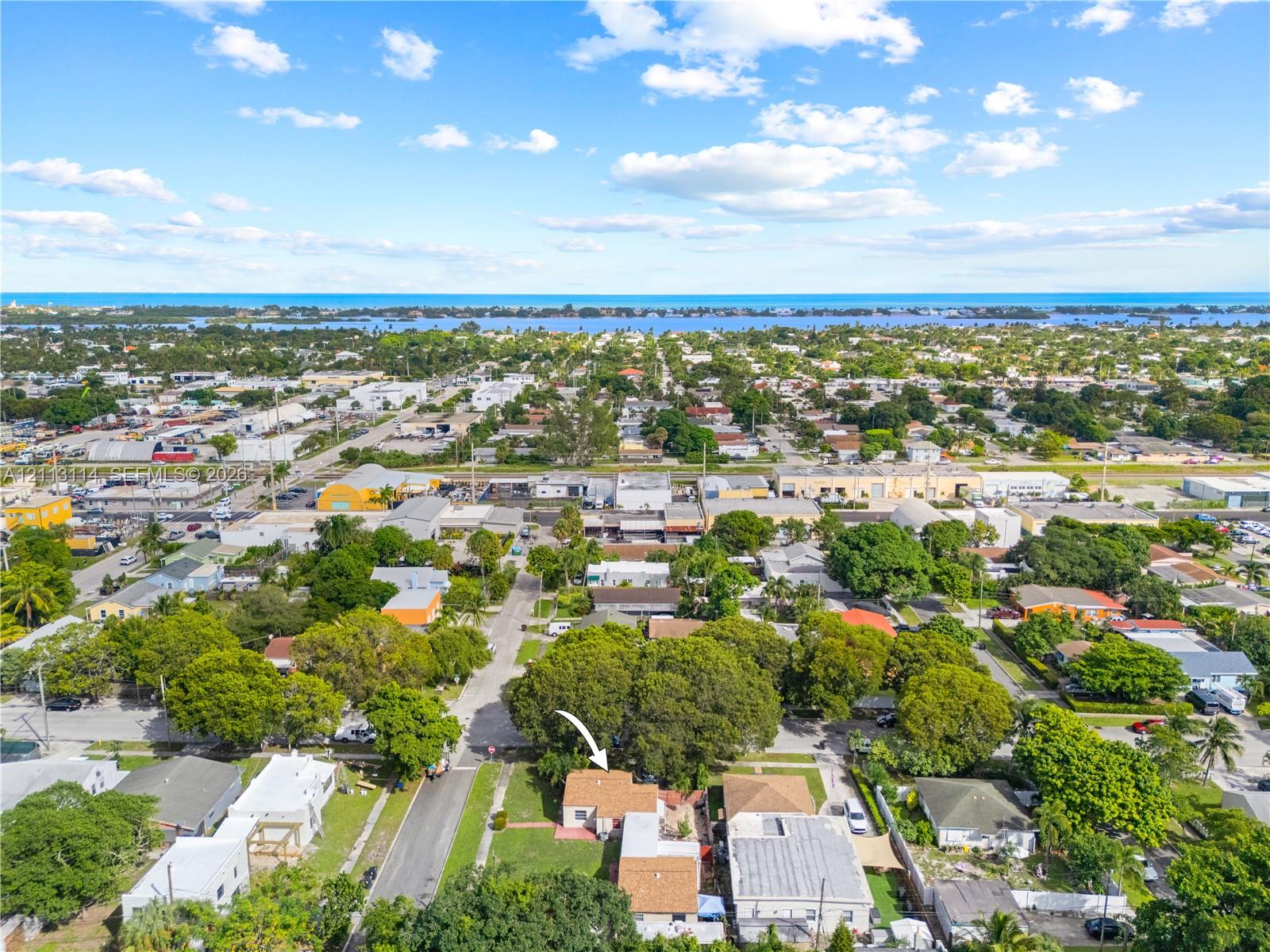 Aerial perspective featuring a single-story residence situated on a lot with mature trees and proximity to the coastline