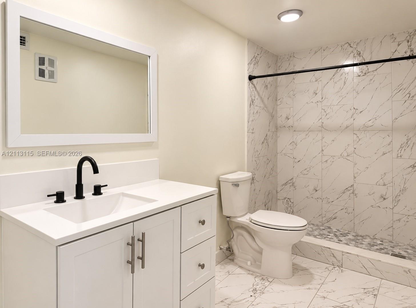 White cabinetry vanity with solid surface countertop, undermount sink, matte black faucet, and full-wall mirror