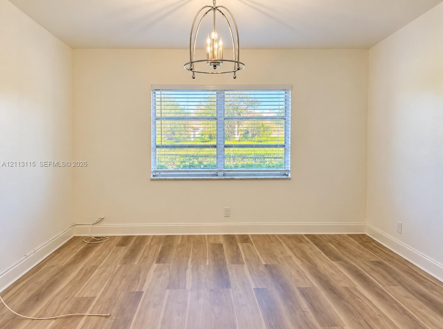 Wood-finish flooring, central metal cage chandelier, and window with horizontal blinds
