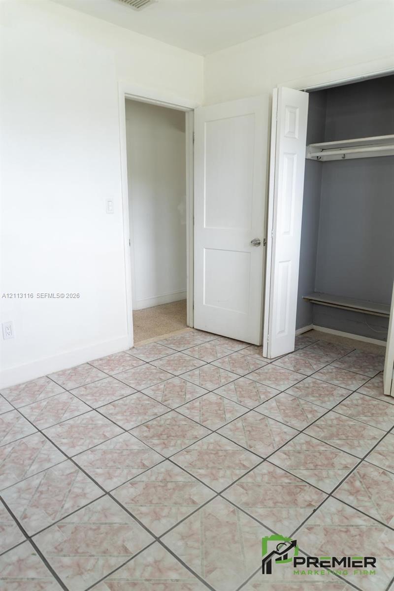 Tile flooring, white two-panel interior door, and built-in closet with overhead shelf and hanging rod