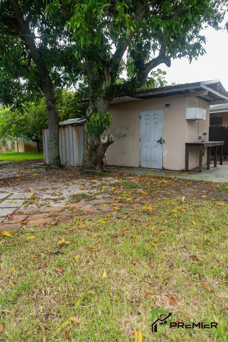 Detached structure featuring a masonry exterior, corrugated metal siding, and a paved stone pathway
