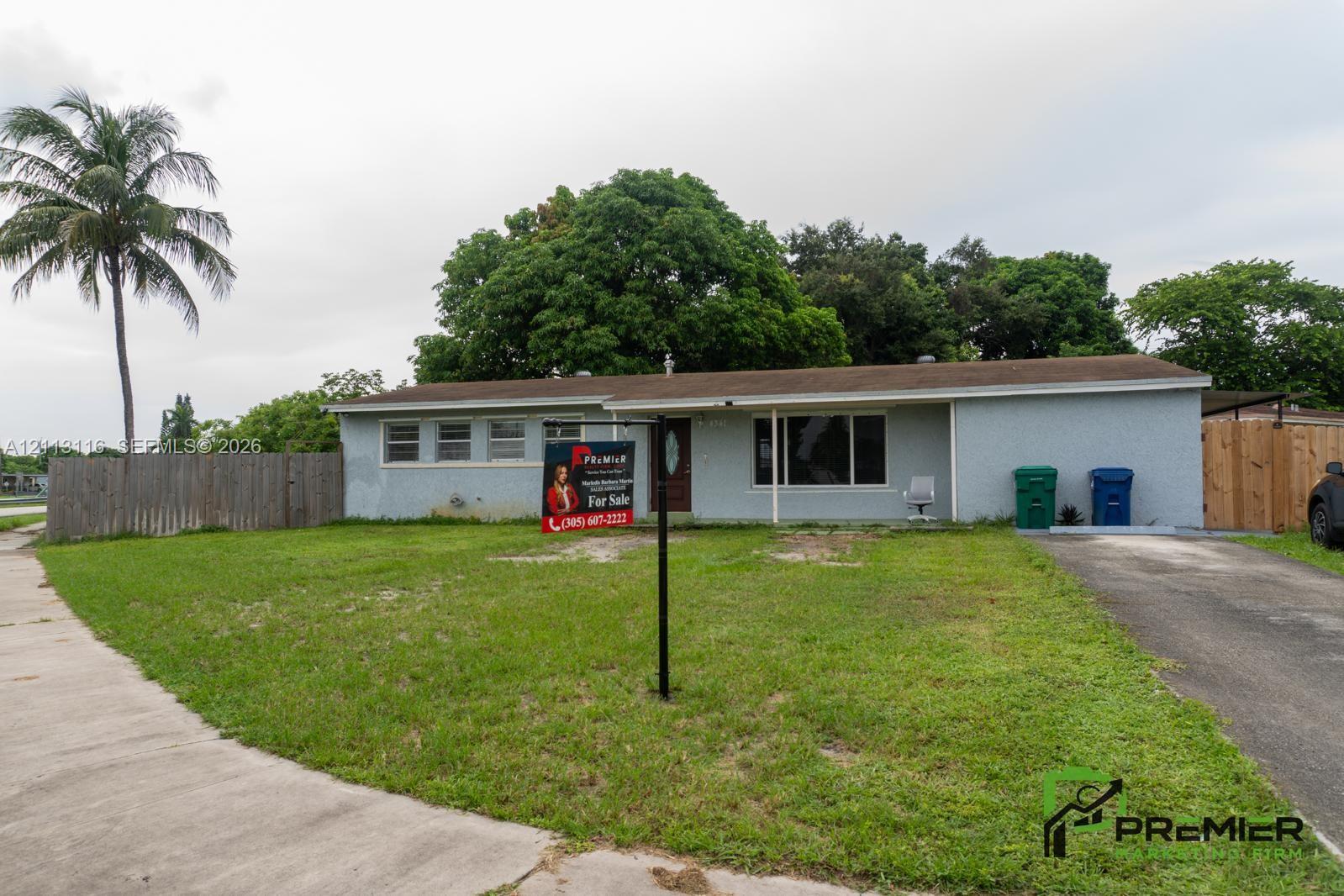 Single-story residence with a stucco exterior, a horizontal-plank wood fence, an asphalt driveway, and mature landscaping