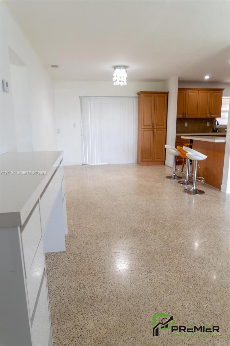 Polished terrazzo flooring throughout, wood-finish cabinetry, built-in floor-to-ceiling storage, and quartz countertop surfaces