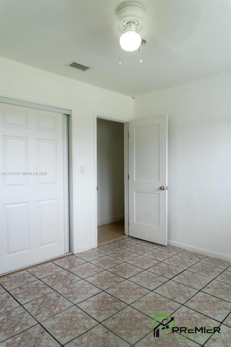 Tiled flooring, dual-panel sliding closet doors, and interior paneled door featuring metallic hardware
