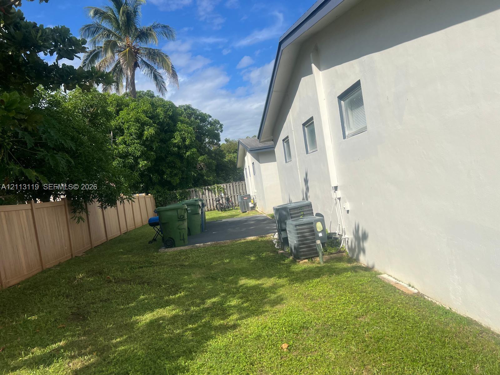 Exterior side yard featuring a concrete pad, vertical wood-panel privacy fencing, and exterior HVAC units