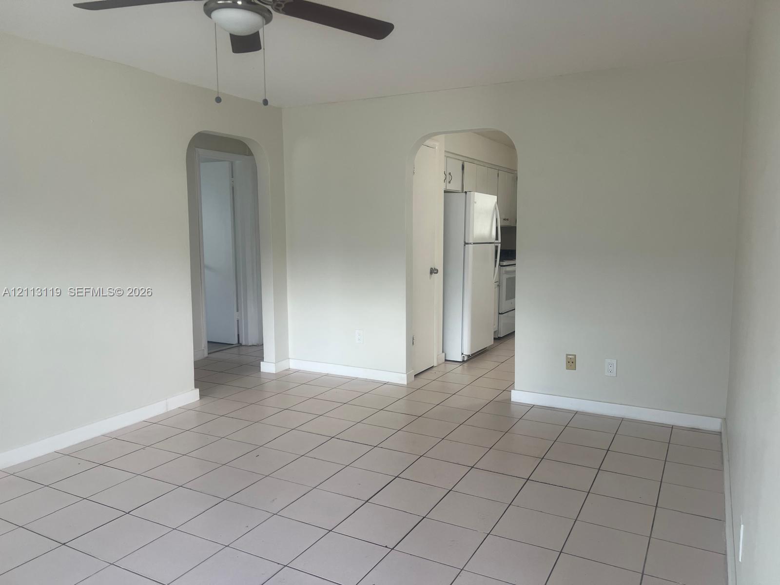Ceramic tile flooring, arched entryways, ceiling fan with light fixture, and neutral wall tones
