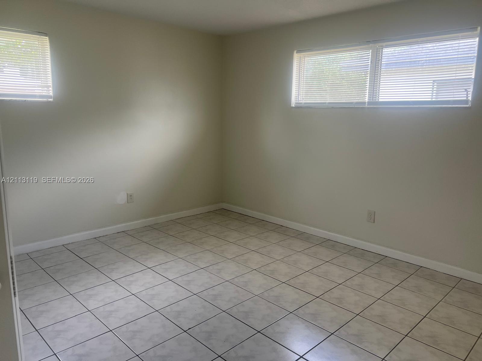 Neutral-toned interior space featuring light-colored tile flooring and multiple horizontal windows