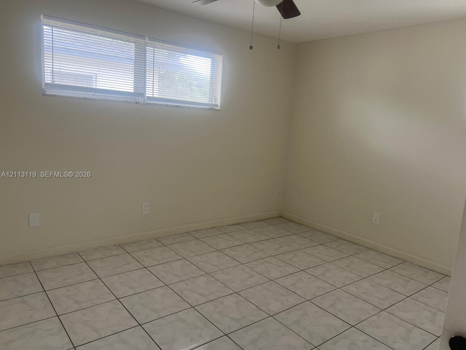 Room featuring neutral-toned walls, tiled flooring, horizontal window blinds, and a ceiling fan