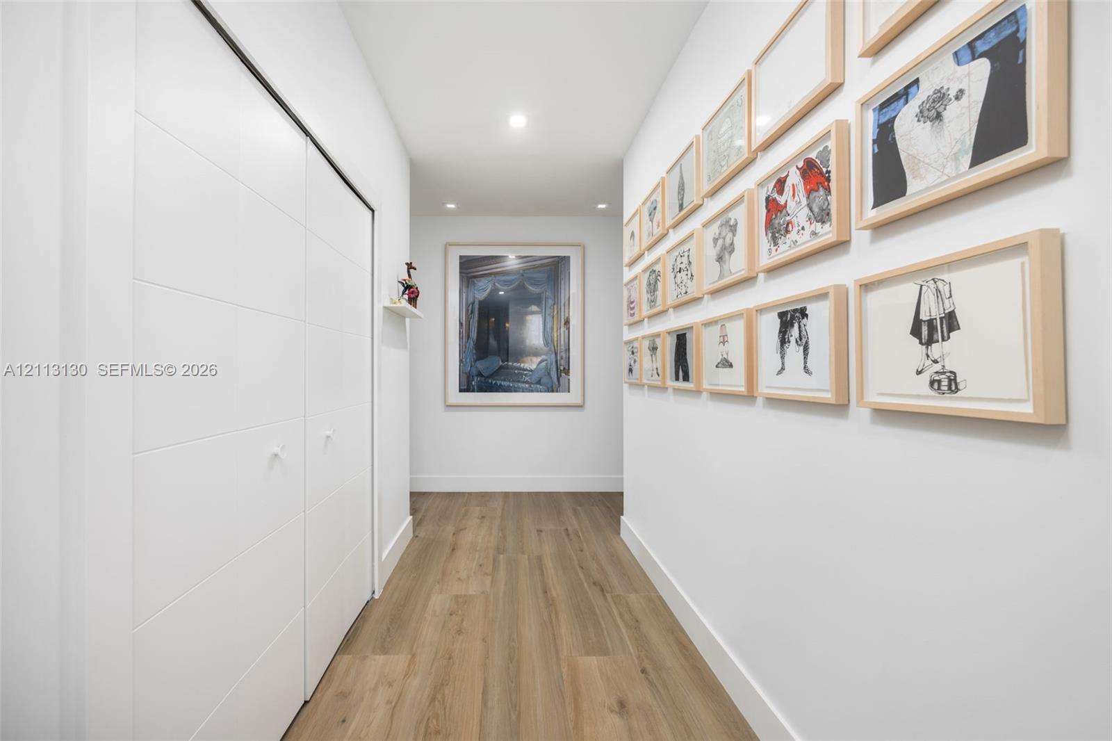 Hallway featuring wood-finish flooring, recessed lighting, and floor-to-ceiling closet doors