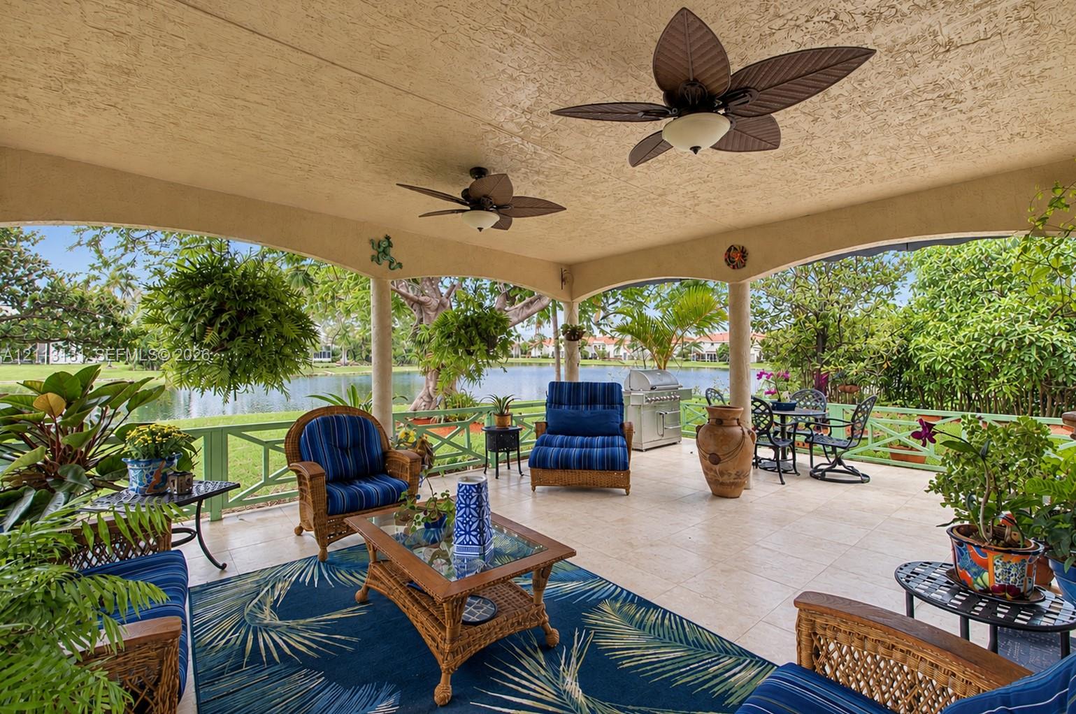 Covered patio featuring a tile floor, arched structural pillars, dual ceiling fans, and a green lattice railing