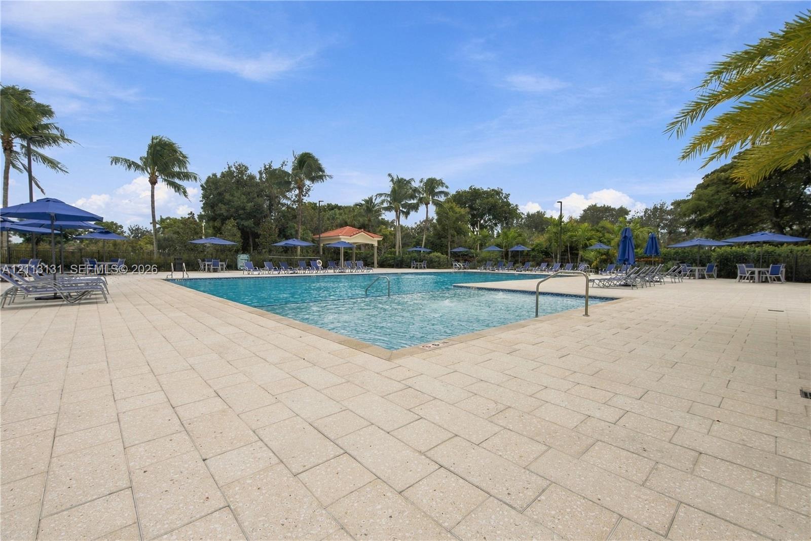 Swimming pool with a sun shelf, paved pool deck, and a covered pavilion