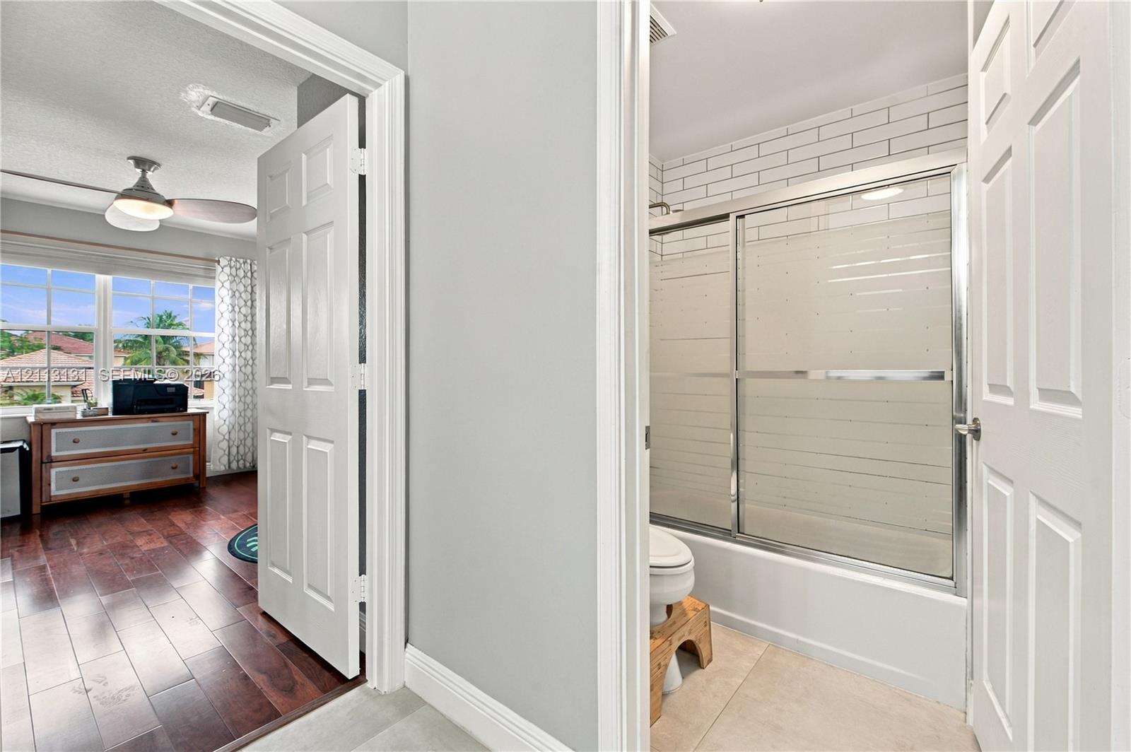 Bathroom featuring white subway tile wall surround, sliding glass shower door enclosure, and neutral floor tiling
