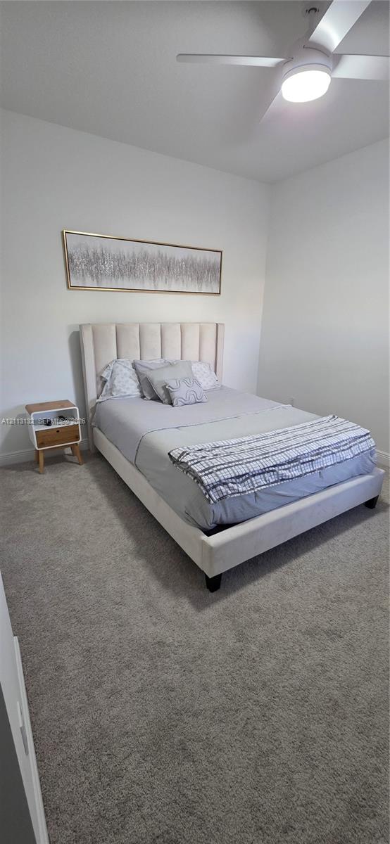 Neutral-toned carpeting, ceiling-mounted fan with integrated lighting, and smooth-finish walls