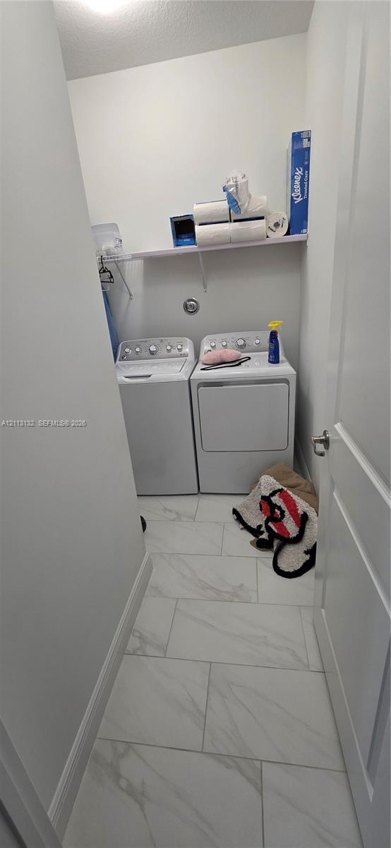Dedicated laundry alcove featuring large-format stone-patterned tile flooring and an integrated wall-mounted shelf