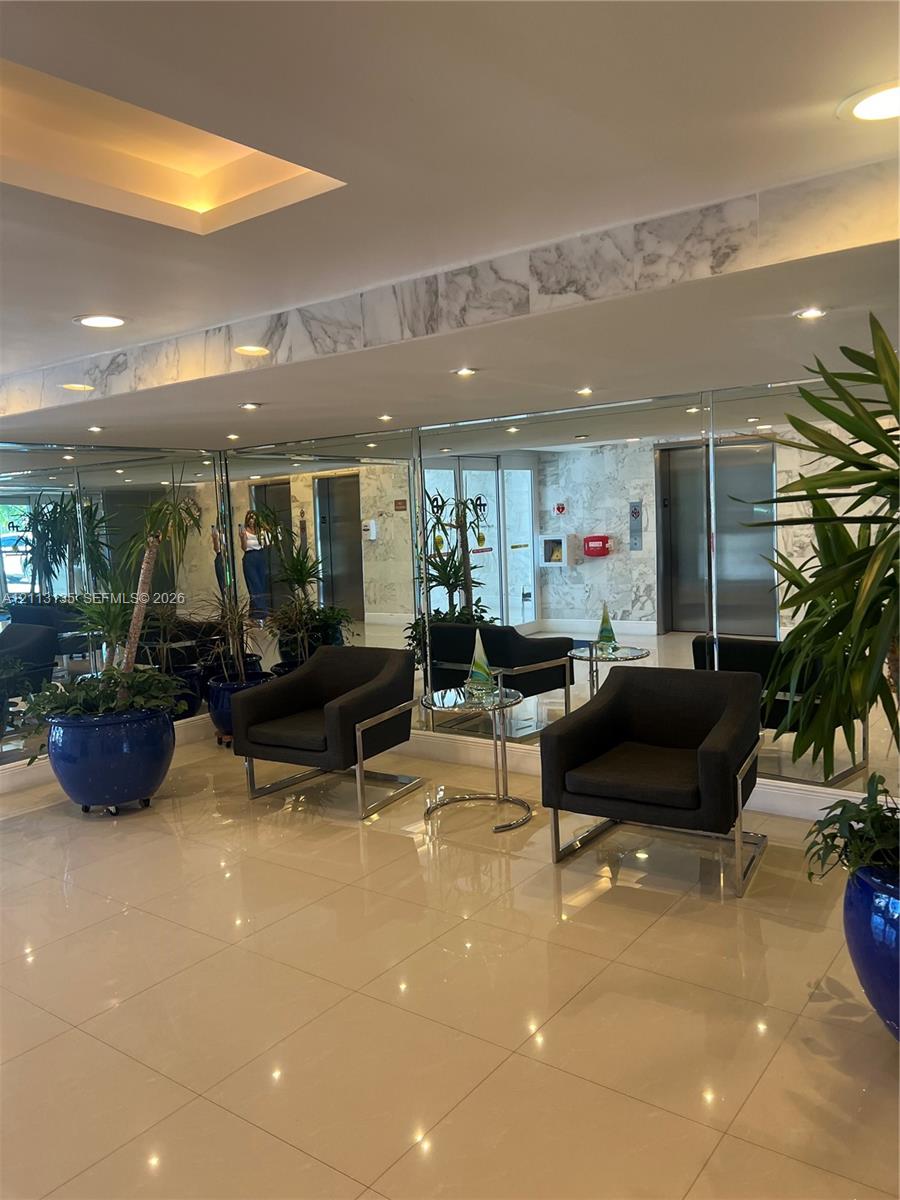 Reflective mirrored walls, recessed tray ceiling lighting, polished tile flooring, and stone-finish wall accents