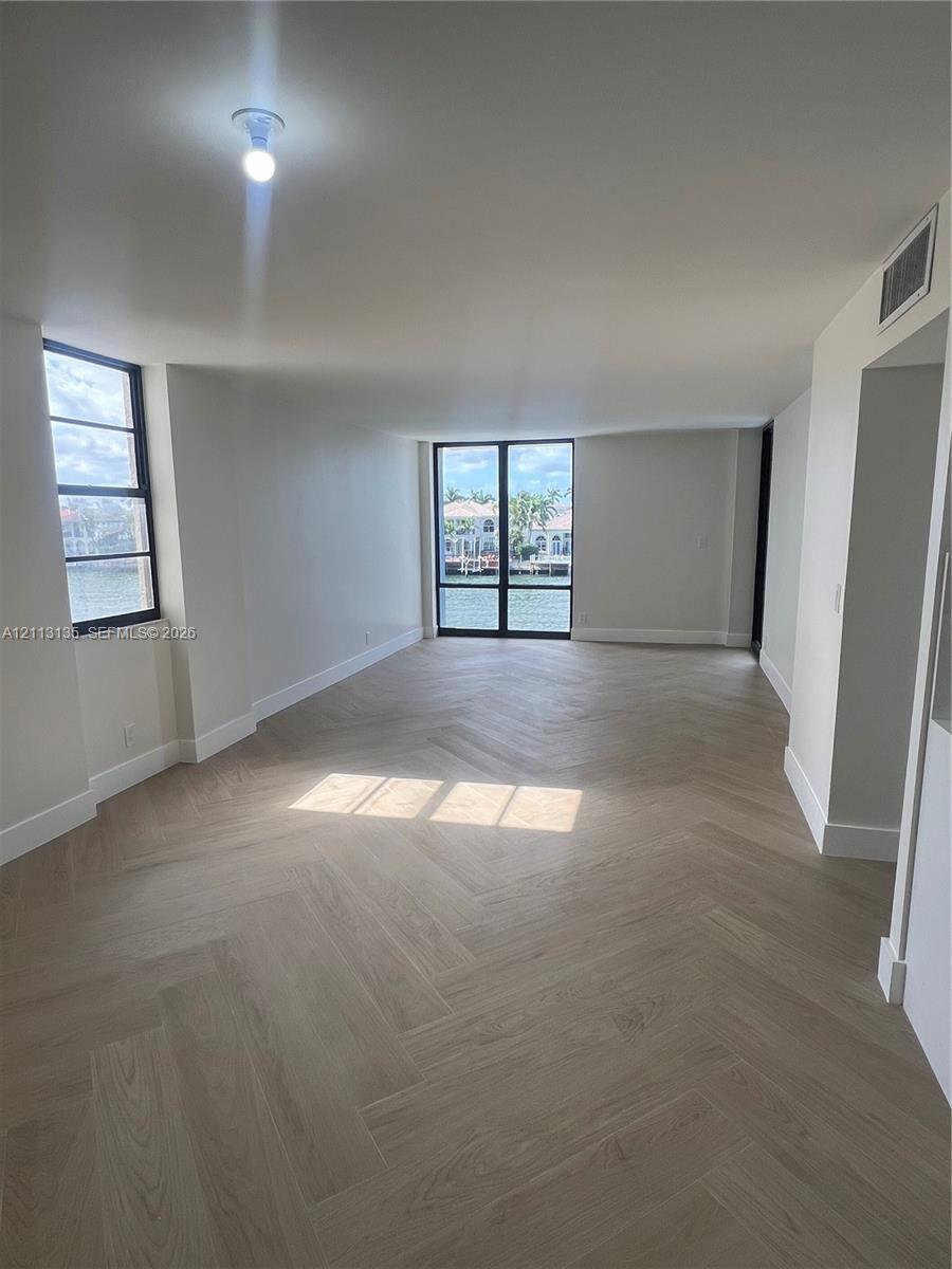 Herringbone wood-finish flooring, floor-to-ceiling windows, and water-facing exterior exposure