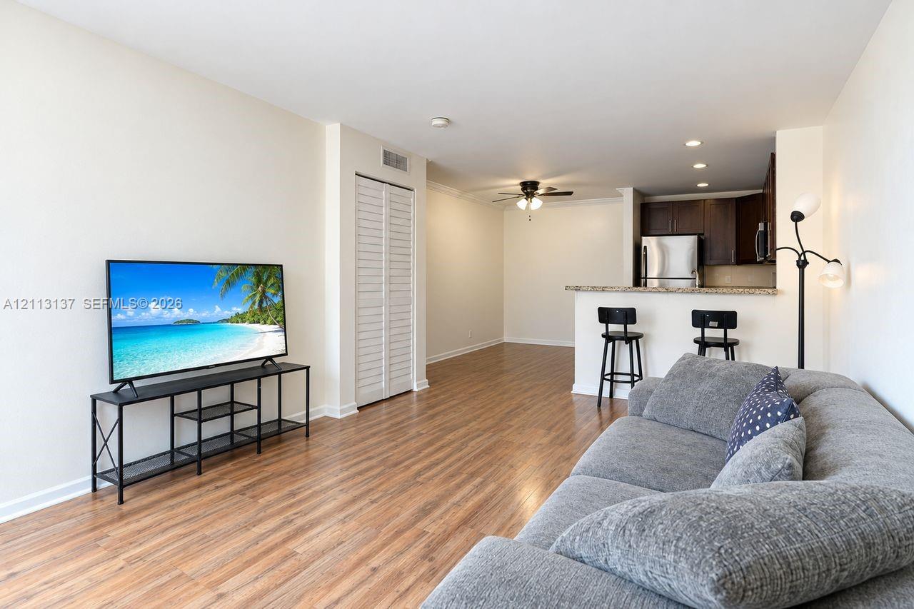 Wood-finish flooring, breakfast bar with stone-finish countertop, stainless steel appliances, dark wood-finish cabinetry, and louvered closet doors Wood-finish flooring, breakfast bar with stone-finish countertop, stainless steel appliances, dark wood-finish cabinetry, and louvered closet doors