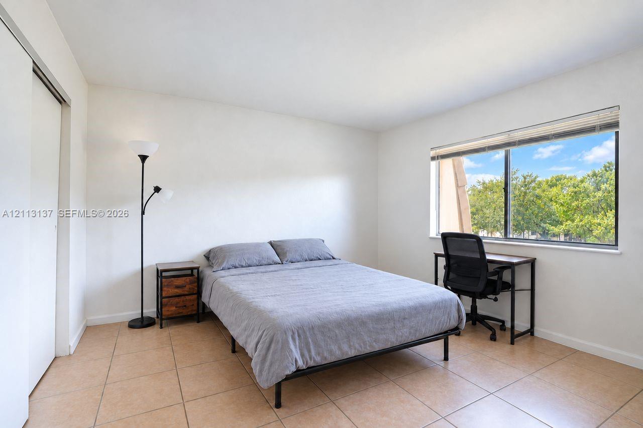 Neutral interior space featuring large-format ceramic tile flooring, a horizontal sliding window, and a sliding closet door