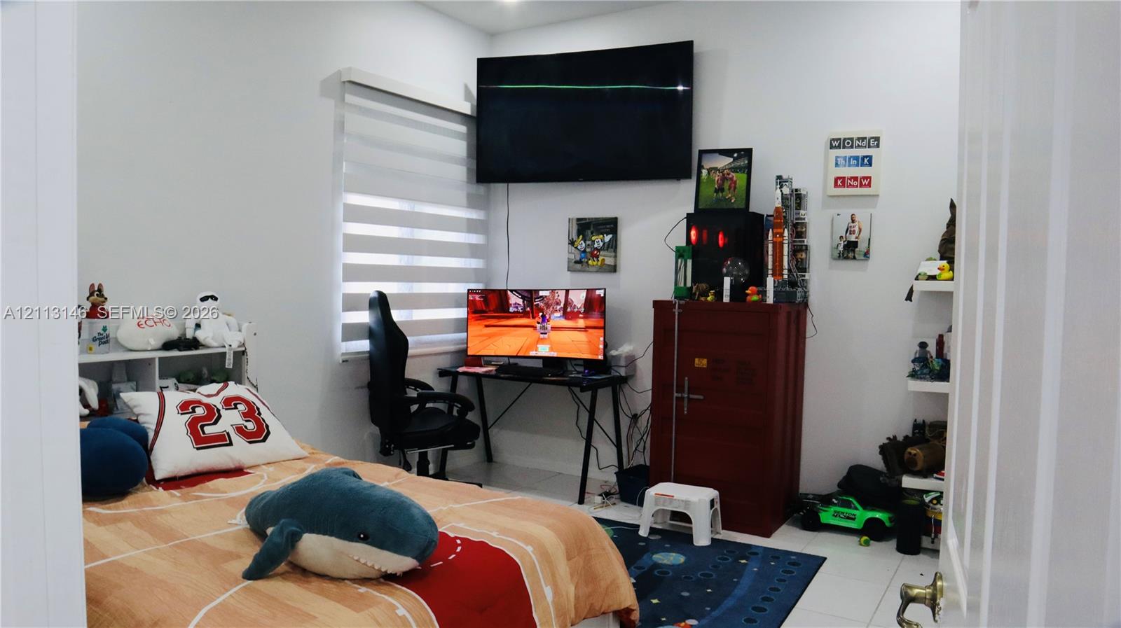 Room featuring neutral wall finishes, light-colored floor tiles, and a window with horizontal blinds Room featuring neutral wall finishes, light-colored floor tiles, and a window with horizontal blinds