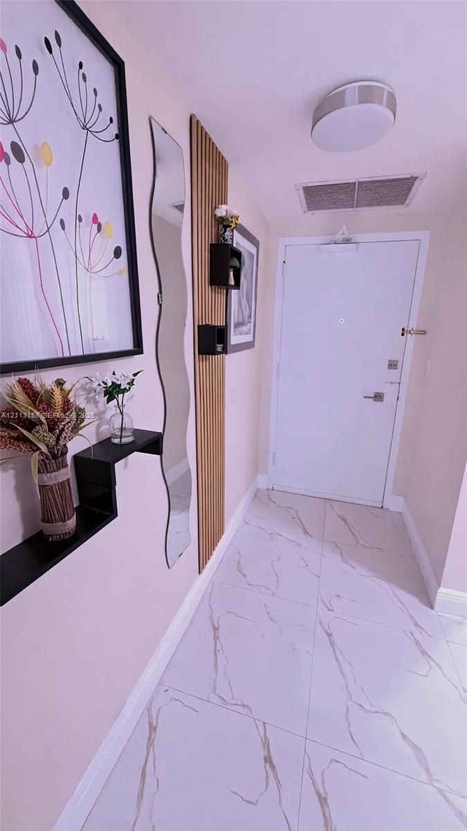 Entryway featuring large-format tile flooring with veining, vertical wood-slat accent wall, and flush-mount ceiling lighting Entryway featuring large-format tile flooring with veining, vertical wood-slat accent wall, and flush-mount ceiling lighting
