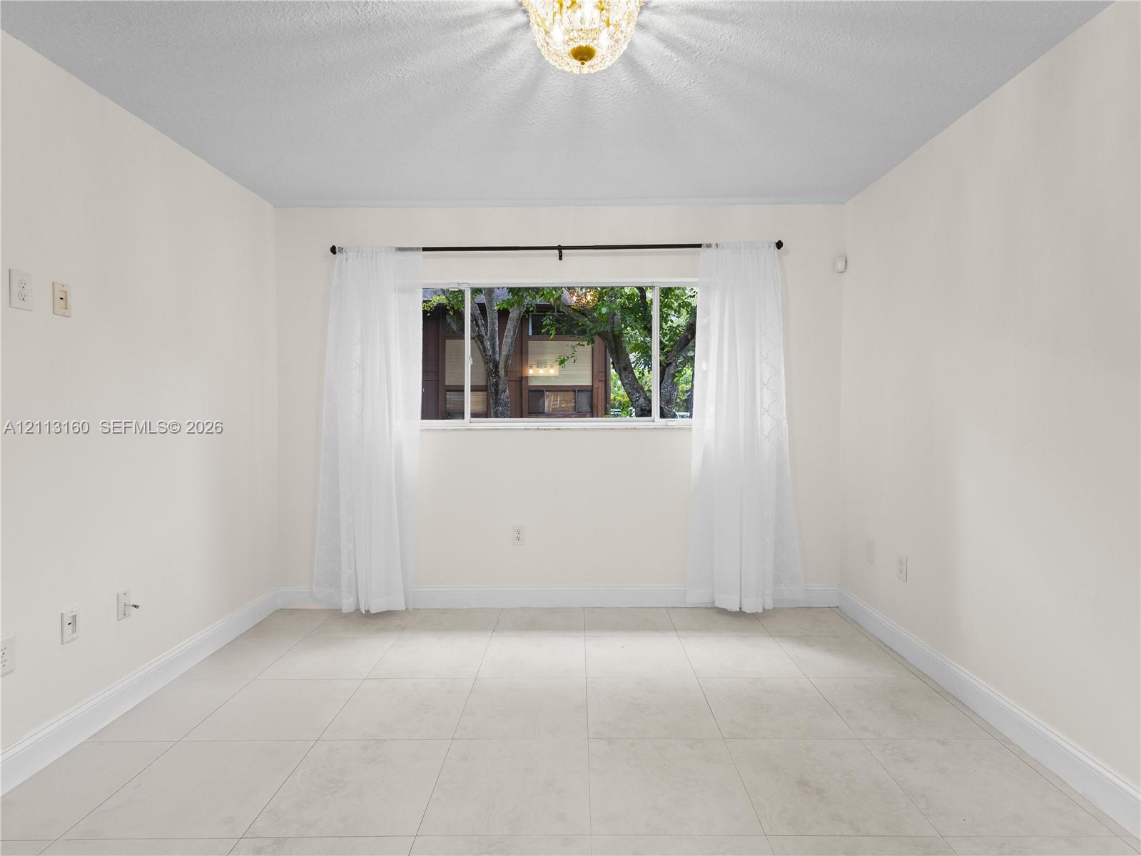 Interior room featuring large-format ceramic tile flooring, a horizontal sliding window, and a central decorative ceiling light fixture