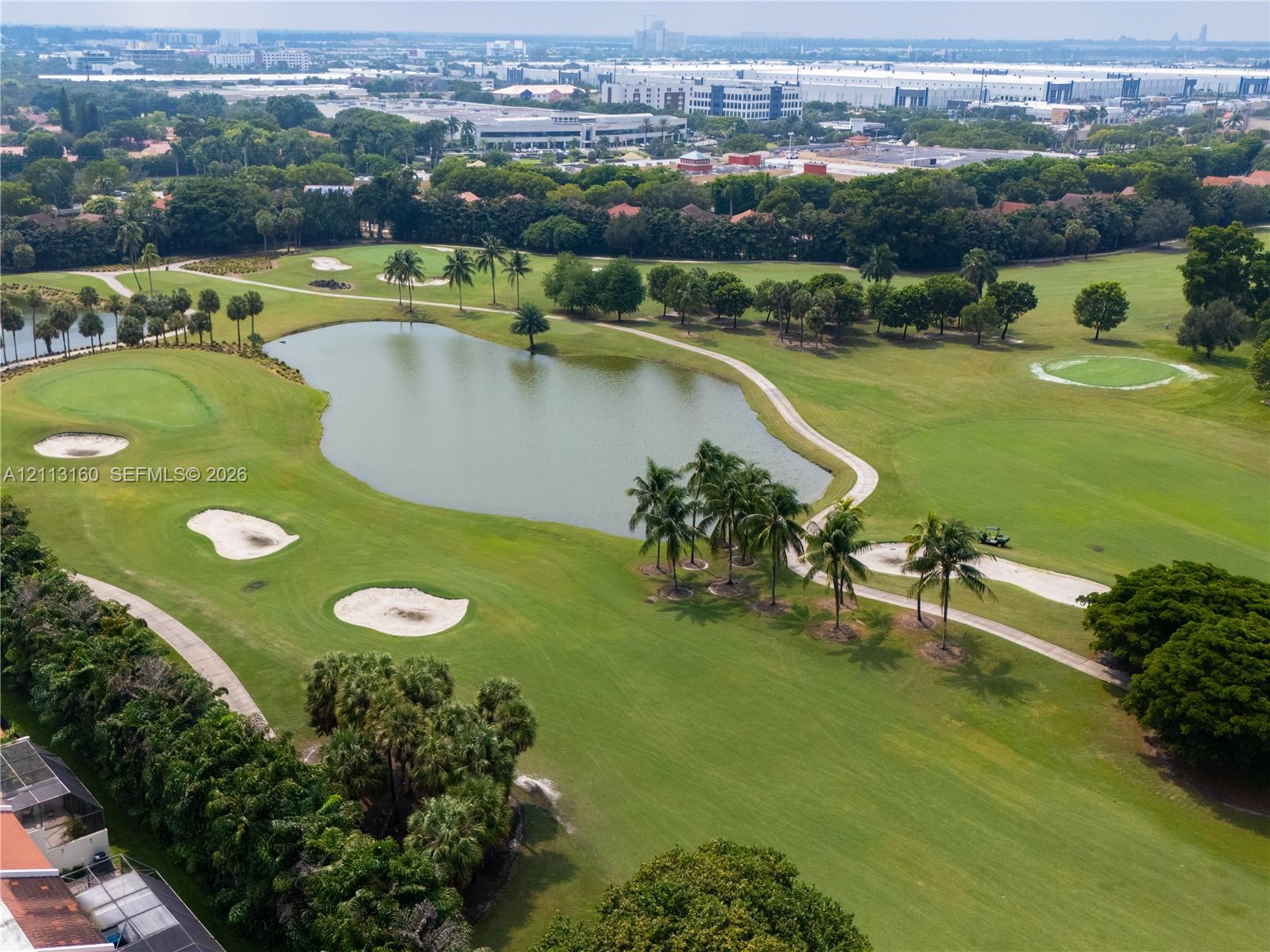 Golf course setting featuring manicured fairways, water features, sand bunkers, and mature palm trees