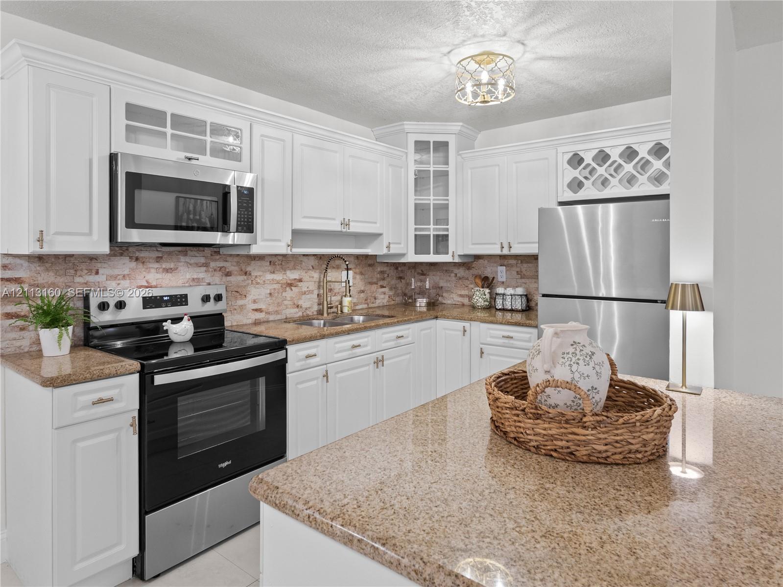 Kitchen featuring white cabinetry, stone countertops, stainless steel appliances, a textured tile backsplash, and built-in wine storage