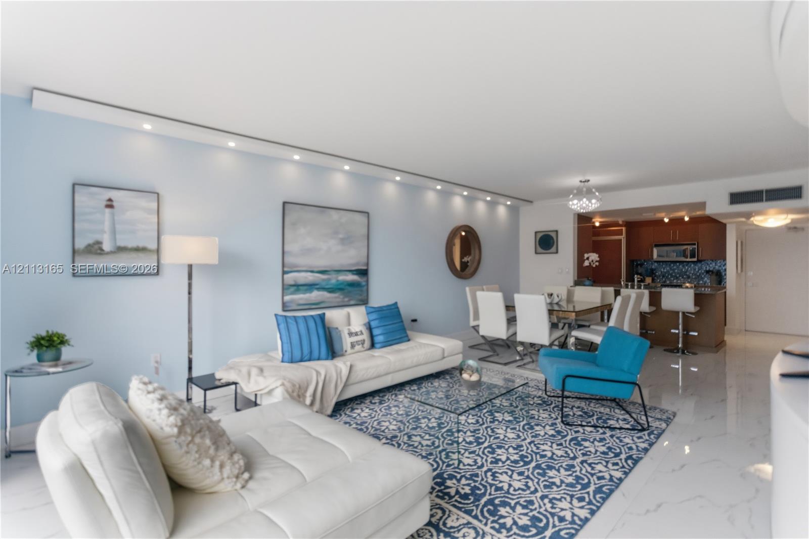 Open-concept interior featuring large-format tile flooring, recessed architectural track lighting, and a kitchen peninsula with integrated seating