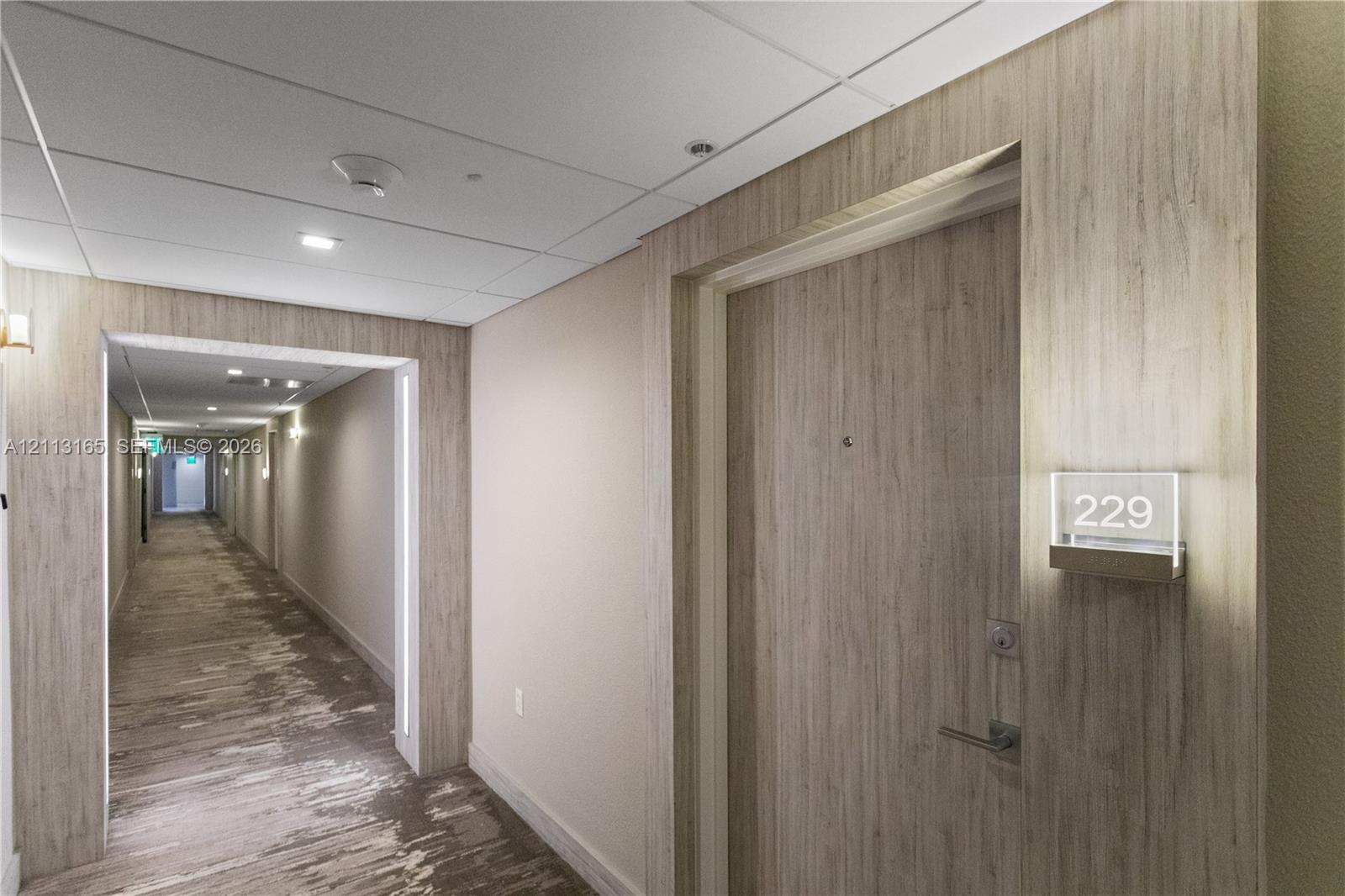 Wood-finish paneling, brushed metallic hardware, integrated door signage, and recessed ceiling lighting