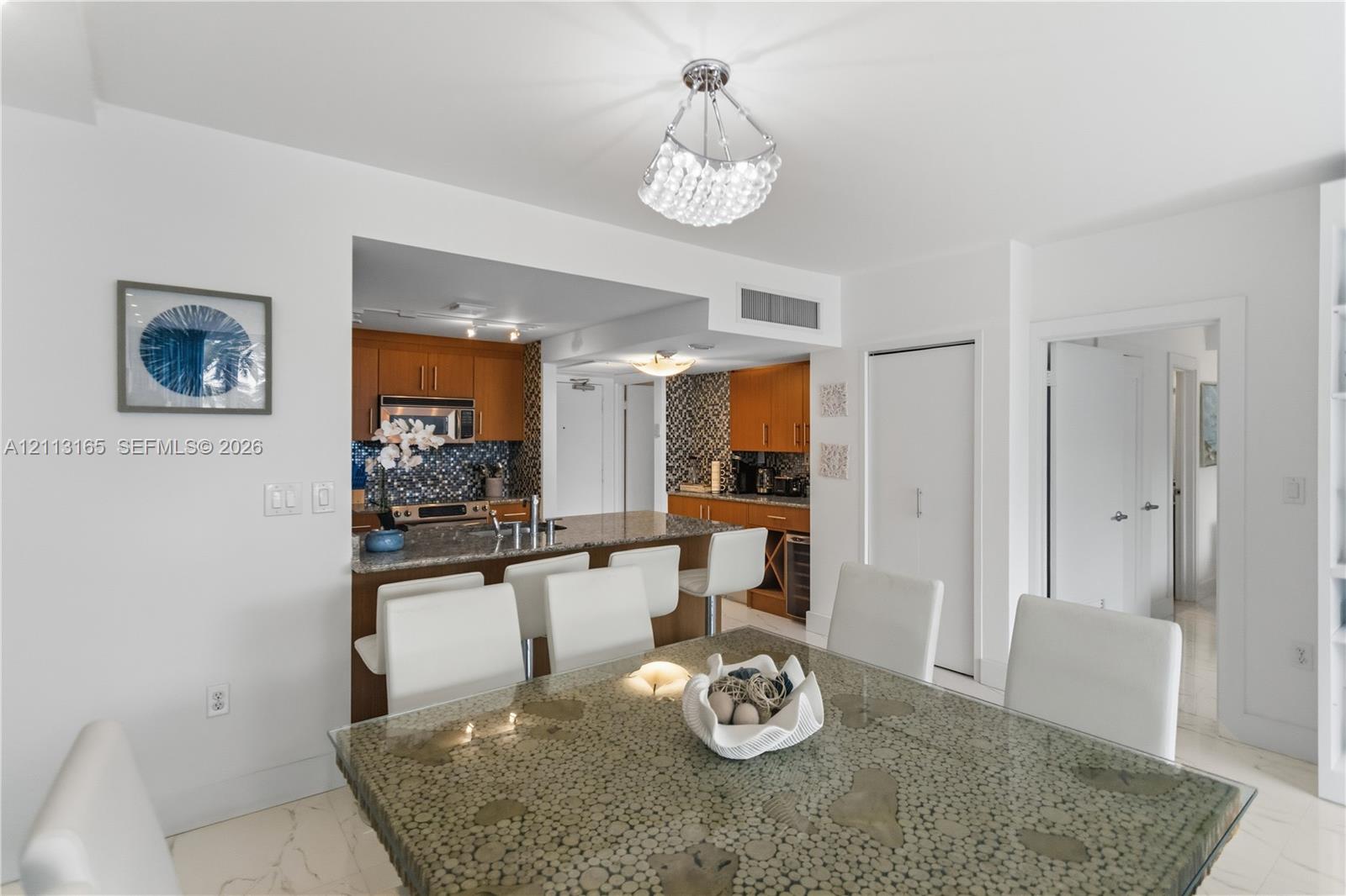 Open-concept kitchen featuring wood cabinetry, stone countertops, a breakfast bar, and decorative tile backsplash