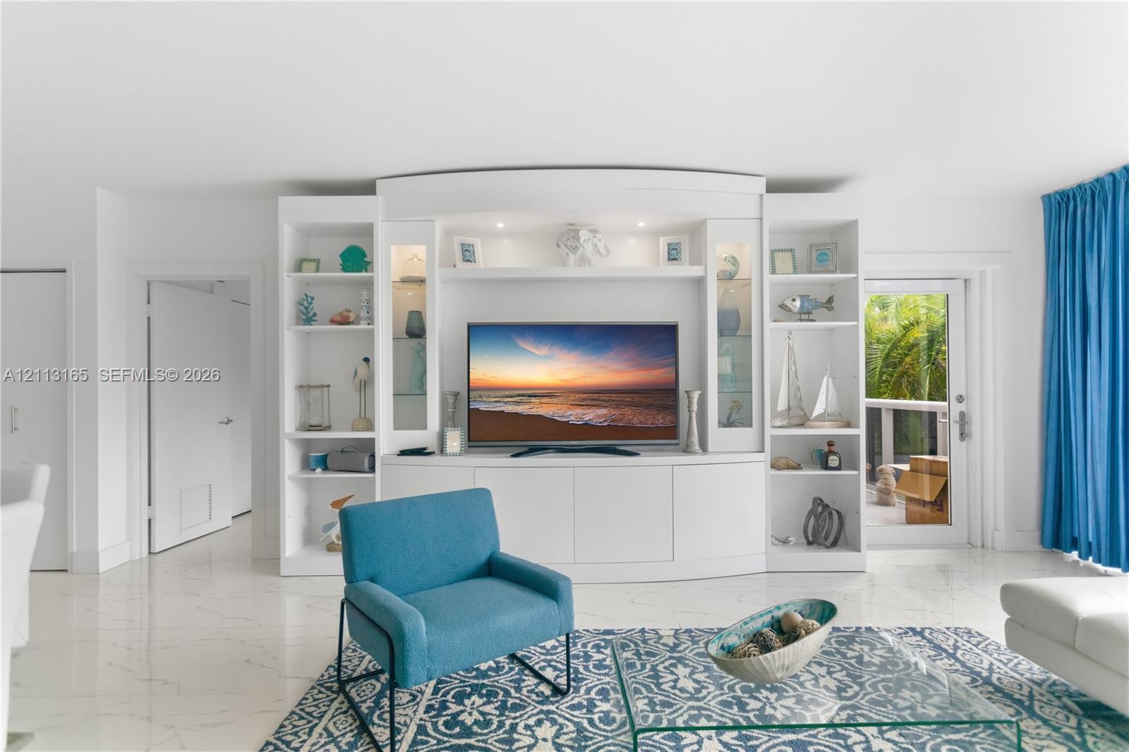 Custom built-in white shelving unit featuring glass-front cabinets, recessed display lighting, and lower storage cabinetry