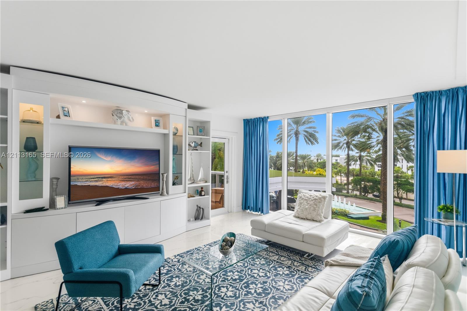 Built-in floor-to-ceiling white cabinetry with integrated display shelving and storage, expansive wall-to-wall glass windows, and polished stone-finish flooring