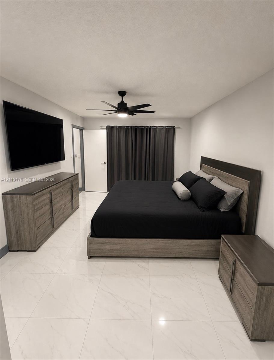Large-format tile flooring, neutral wall tones, and a ceiling-mounted matte black fan