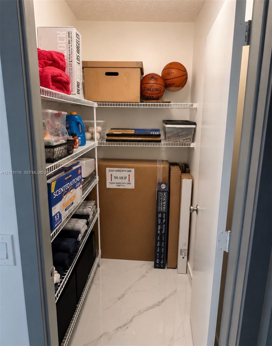 Storage closet featuring white wire shelving and stone-finish tile flooring