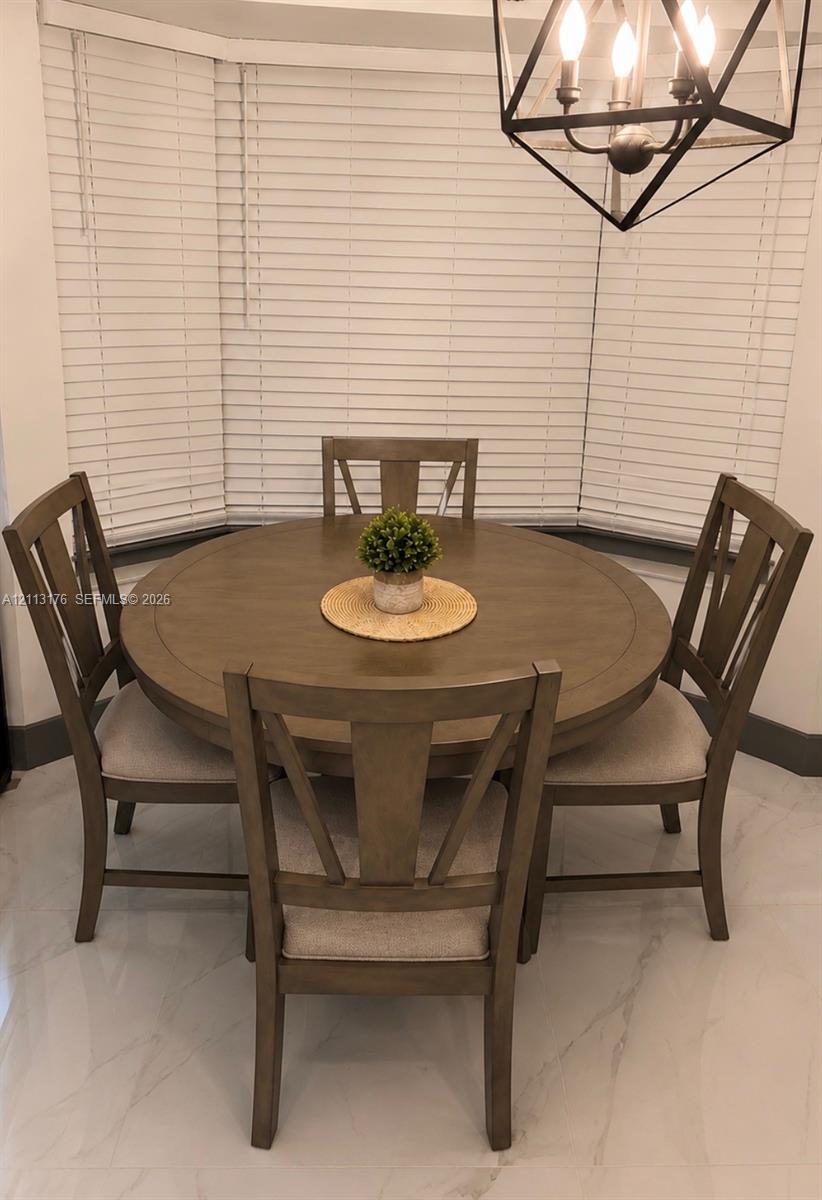 Bay window featuring horizontal blinds, large-format tile flooring, and a geometric metal pendant light fixture