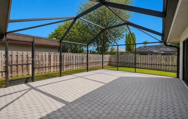 Screened-in patio featuring a paved floor, metal frame, and wood fencing