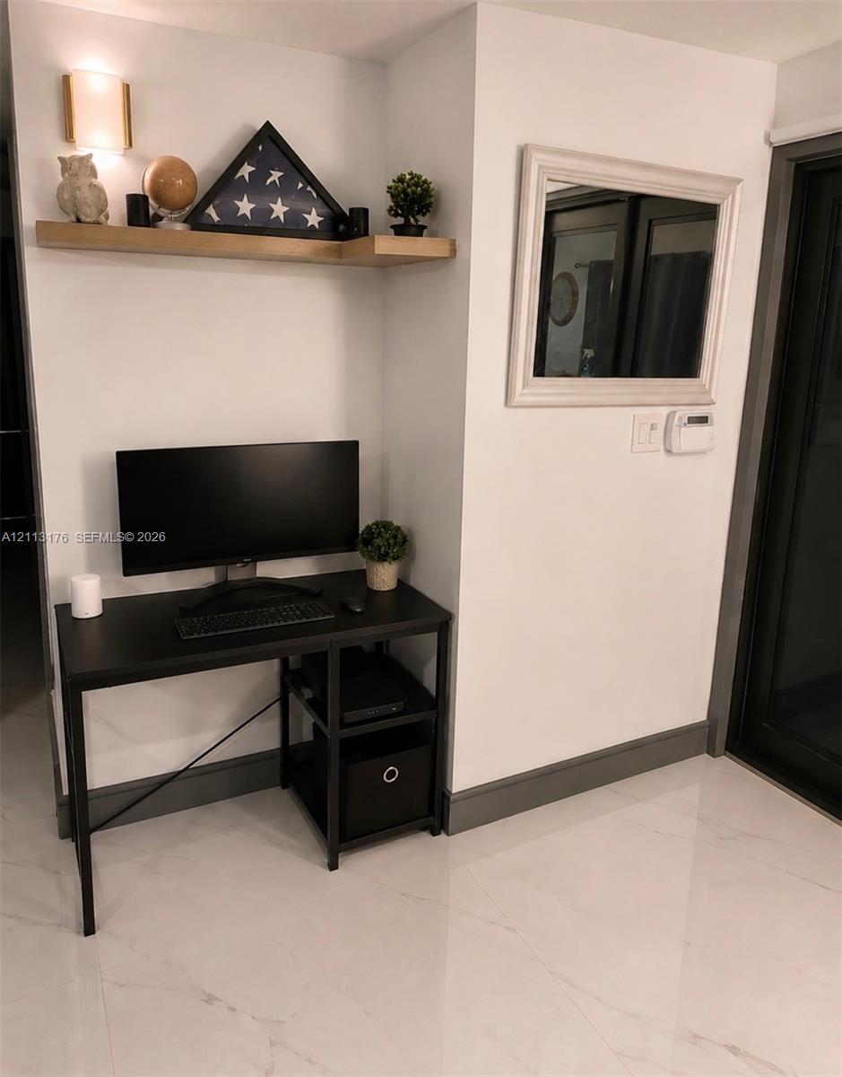Built-in wall-mounted wood shelf with integrated sconce lighting, polished stone-finish flooring, and dark-toned trim