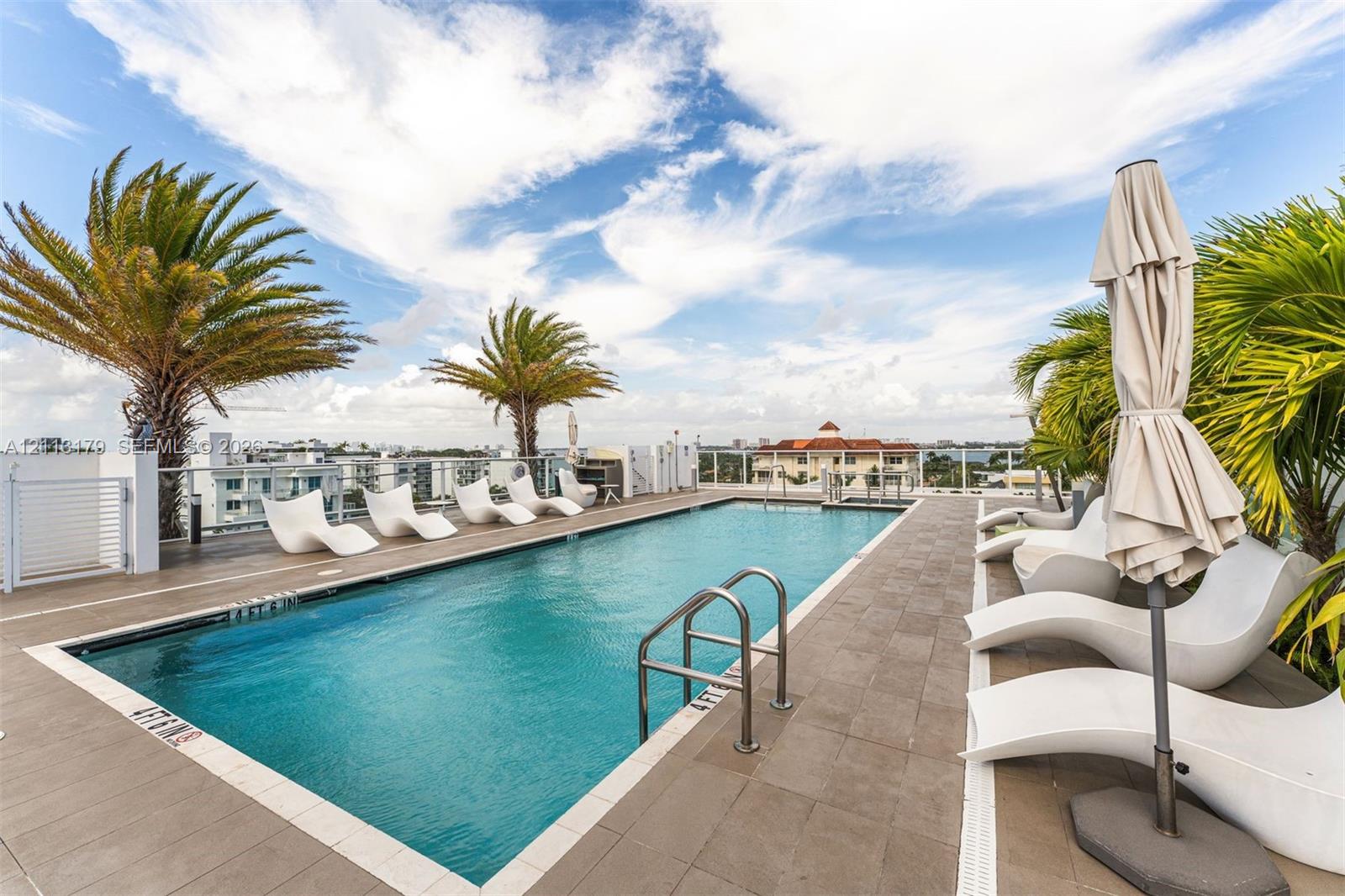 Rooftop swimming pool featuring tile decking, stainless steel handrails, and glass perimeter railings
