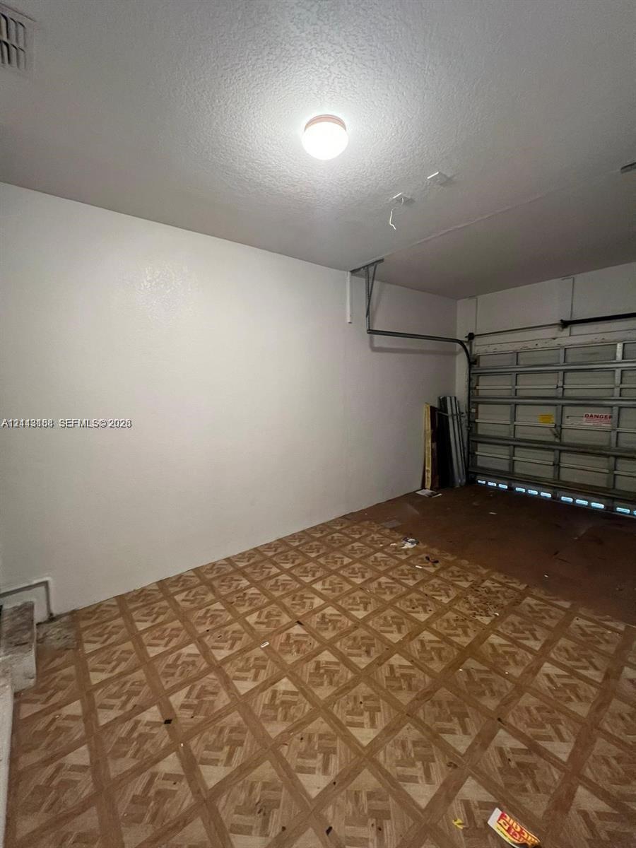 Garage space featuring patterned flooring, smooth wall finishes, and a sectional overhead door