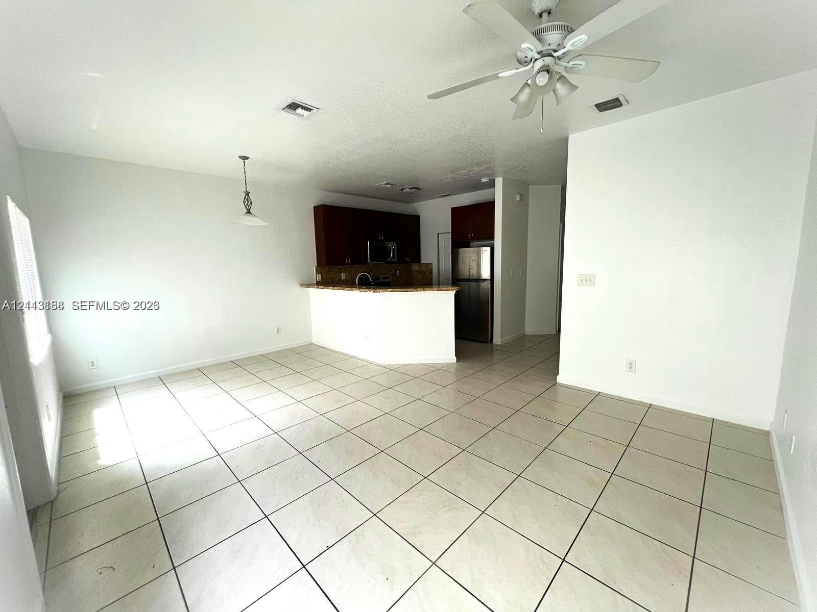 Kitchen featuring a breakfast bar, dark-finish cabinetry, stainless steel refrigerator, and ceramic tile flooring throughout