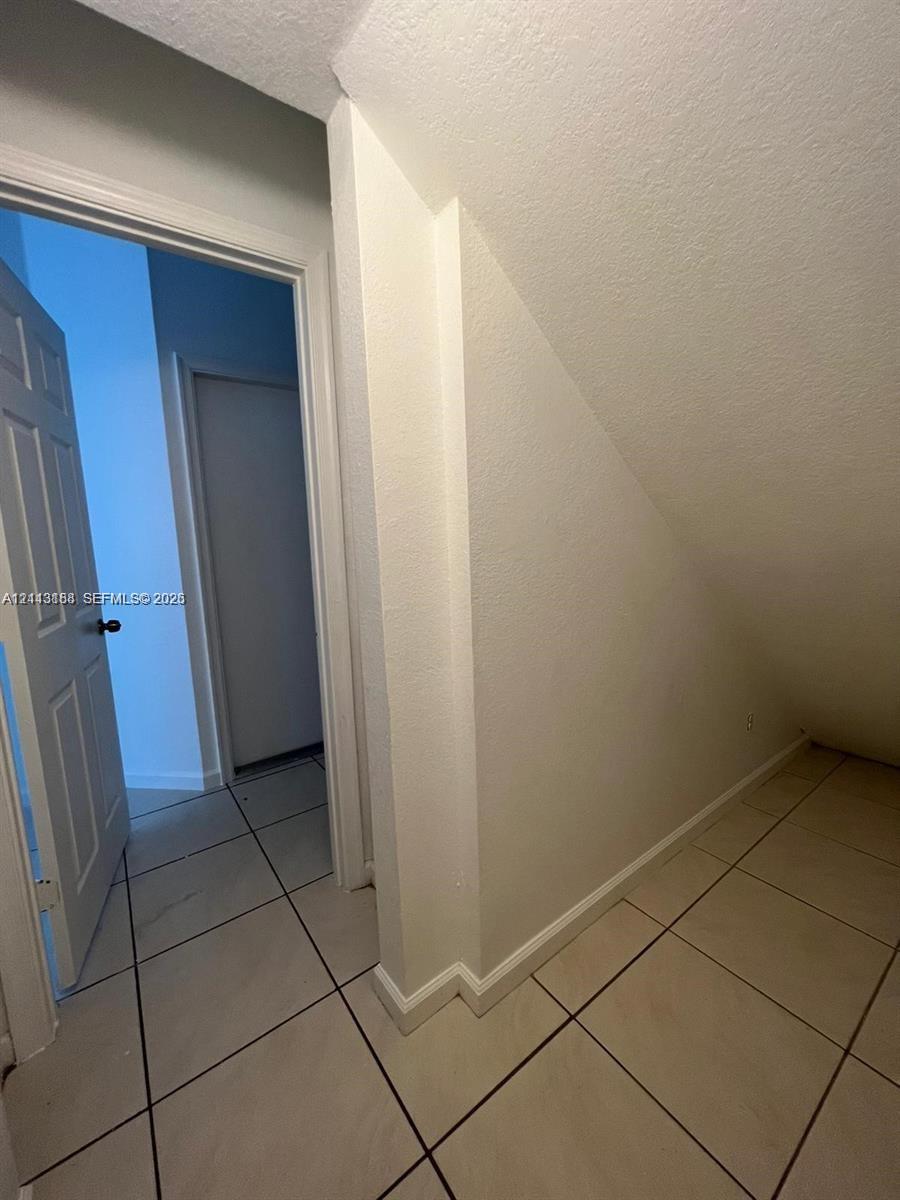 Interior storage space featuring tile flooring, smooth walls, and a multi-panel door